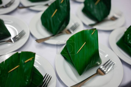 Téléchargez les photos : Enveloppement de dessert thaïlandais avec feuille de banane fraîche sur soucoupe en céramique préparée pour les pauses servies entre les séminaires - en image libre de droit