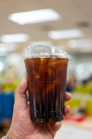 Téléchargez les photos : Tenue jetable café noir glacé dans une tasse en plastique avant de boire. - en image libre de droit