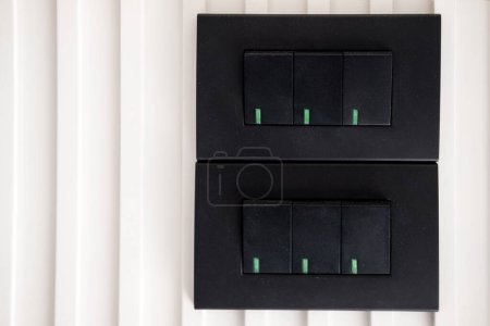 Two pairs of Black light switches on white wall. Element of modern interior design with black electric light switch