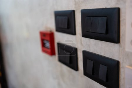Interruptores de luz negro y despertador de incendios en la pared de cemento