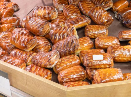 Freshly baked crispy bread buns on a counter or shelf in a store, close-up. Bakery products are sold in the market. Fresh bakery. Assortment of pastries. Close-up.