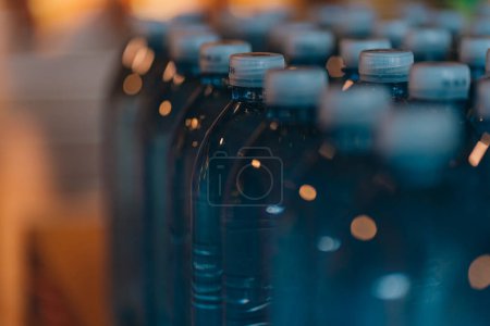 Foto de Primer plano de botellas de plástico de agua cruda. Línea de botellas de agua mineral azul, bebida natural transparente - Imagen libre de derechos