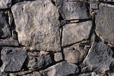 Grunge stone wall built with granite rock construction materials.
