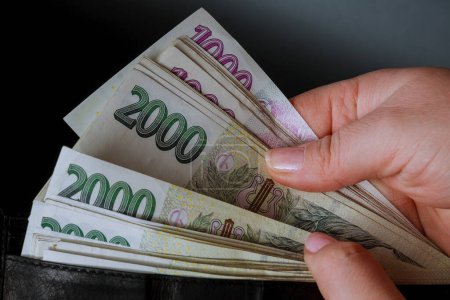 In einem schwarzen Portemonnaie befinden sich Scheine über zweitausend Kronen, tschechisches Geld. Geld in den Händen eines Bankers, Neuberechnung des Geldes.