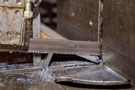 Foto de Corte de perfiles y tuberías de acero en una sierra de cinta en producción. - Imagen libre de derechos
