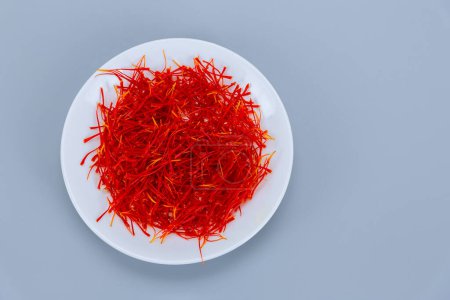 Saffron stamens in a white plate on a white background, place for text. drying of saffron stamens, saffron spice.