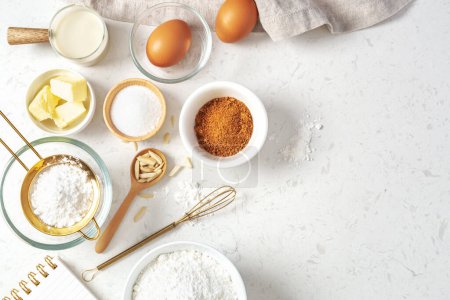 Photo for Baking pastry or cake ingredients, brown sugar, butter, flour, eggs and milk with utensil on marble table, top view with copy space - Royalty Free Image