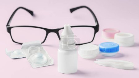 Photo for Eye drops bottle with contact lens, eyeglasses and accessories on pink background - Royalty Free Image