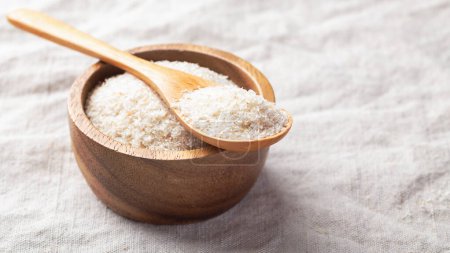 Psyllium husk in spoon on wooden bowl, fiber food for diet on linen table cloth background, copy space