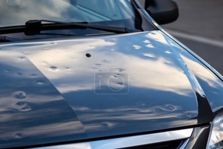 Téléchargez les photos : Black car engine hood with many hail damage dents show the forces of nature and the importance of car insurance and replacement value insurance against hail dents of storm hazards extreme weather - en image libre de droit
