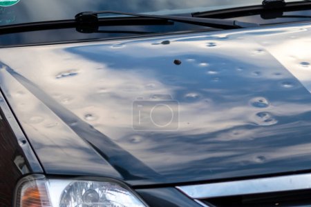 Téléchargez les photos : Black car engine hood with many hail damage dents show the forces of nature and the importance of car insurance and replacement value insurance against hail dents of storm hazards extreme weather - en image libre de droit