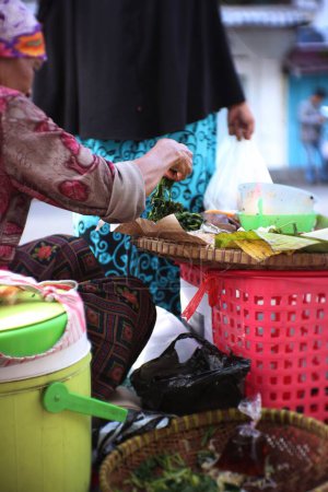 Photo for An old Indonesian woman is preparing "Pecel dishes" for customers. Pecel cuisine is a traditional food from Indonesia - Royalty Free Image