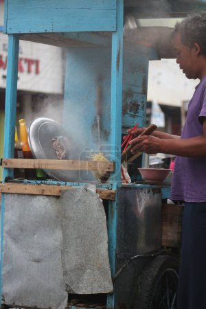 Photo for An Indonesian penjual mie ayam bakso or meatball chicken noodle seller who is making chicken noodles for the buyer. - Royalty Free Image