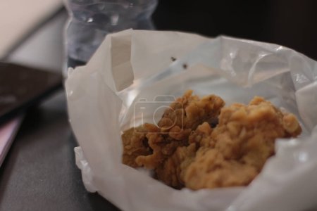 Téléchargez les photos : "Le poulet frit croustillant est enveloppé dans un sac en plastique blanc." - en image libre de droit