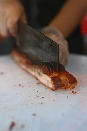 Pork is being cut on a white cutting board