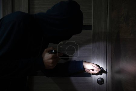 Foto de Hombre ladrón colándose en la casa con flashligh - Imagen libre de derechos