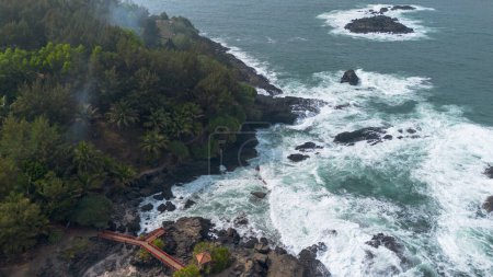 Téléchargez les photos : Vue sur les drones La beauté de Menganti Beach, Kebumen, Java central, Indonésie, une plage avec des vagues de mer calmes et des falaises de corail et des arbres verts - en image libre de droit