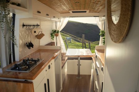 Interior of a cozy camper with Nordic design in a bucolic landscape surrounded by cows at sunset. Lifestyle, travel, tourism, outdoors
