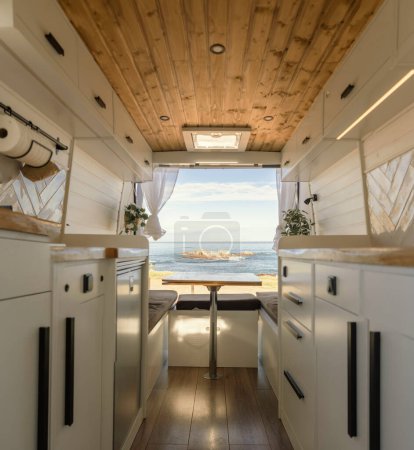 Interior of a cozy camper with Nordic design in front of a beach landscape.Lifestyle, travel, tourism, outdoors