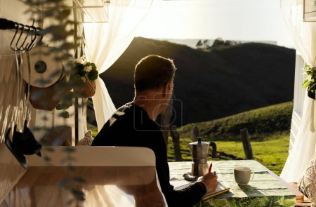 Man reflecting while observing nature from a camper van at sunset. People, lifestyle, travel, tourism, outdoors