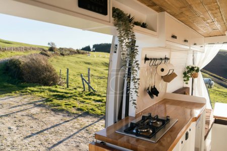 Interior of a cozy camper with Nordic design in a bucolic landscape surrounded by cows at sunset. Lifestyle, travel, tourism, outdoors