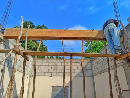 Foto de Esta foto captura a un albañil elaborando meticulosamente una nueva columna durante la restauración de una antigua casa en Guatemala, mezclando técnicas de construcción tradicionales con prácticas modernas de restauración para asegurar la fidelidad cultural y la resiliencia estructural. - Imagen libre de derechos