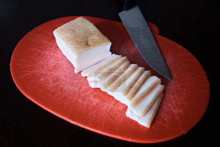 Foto de Demonstration of sliced pork lard in thin slices from a large piece. Close-up - Imagen libre de derechos