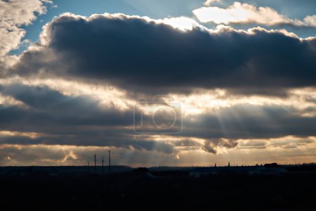 Téléchargez les photos : Les rayons d'hiver du soleil traversent d'épais nuages gris. - en image libre de droit