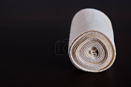 Photo for Dirty, used medical elastic bandage on a dark background. Twisted into a roll. Concept of medicine. - Royalty Free Image