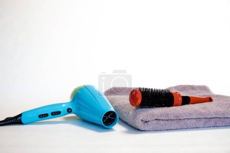 Foto de Secador de pelo, toalla y peine sobre fondo blanco. Procedimientos de spa. Lugar para el texto. cerrar - Imagen libre de derechos