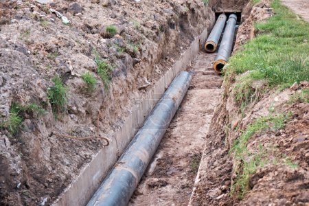 Téléchargez les photos : Pose de nouveaux tuyaux d'eau dans un fossé en béton. Ligne thermique. - en image libre de droit