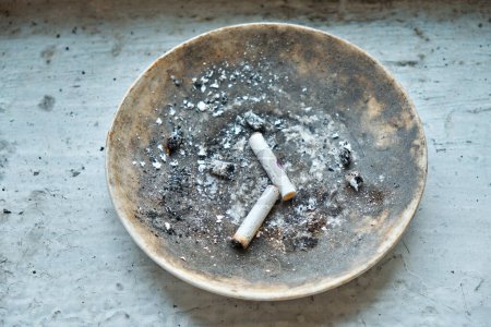 Foto de Colillas de cigarrillos se encuentran en un plato en el alféizar de la ventana. - Imagen libre de derechos