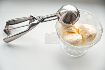 Photo for Scoops of ice cream in a glass jar and a dispenser-spoon for ice cream. - Royalty Free Image