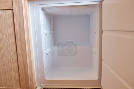 Freezer with ice on the walls in the built-in refrigerator.