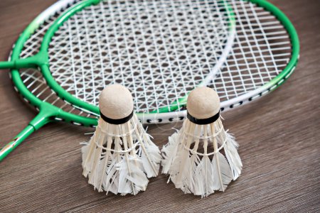 Photo for Two shuttlecocks and two badminton rackets on a dark background. Professional sports equipment. - Royalty Free Image