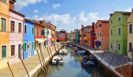 Burano Postkarte. Bunte Häuser auf der Insel Burano. Bunte Gebäude am Fundamentdamm eines schmalen Wasserkanals mit Fischerbooten an sonnigen Tagen, Provinz Venedig, Region Venetien, Norditalien. 