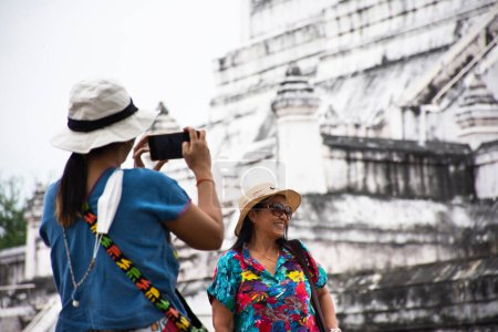 Téléchargez les photos : Mère aînée thaïlandaise et jeunes filles femmes voyage visite et pose portrait pour prendre des photos après le respect priant bénédiction bouddha sainte au temple Wat Phu Khao Thong à Phra Nakhon Si Ayutthaya Thaïlande - en image libre de droit