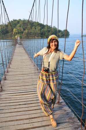 Foto de Travelers thai women photographer journey travel visit and posing portrait take photo on wooden suspension bridge crossing lake to island at Kaeng Krachan Dam National Park in Phetchaburi, Thailand - Imagen libre de derechos
