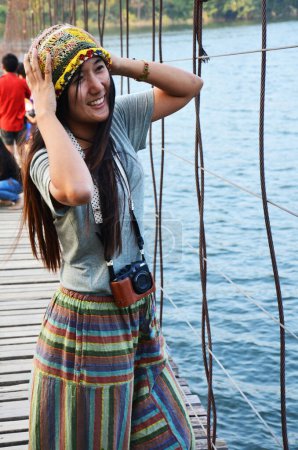 Foto de Viajeros tailandeses fotógrafas visitan y posan retrato toman foto en puente colgante de madera cruzando lago a isla en la presa Kaeng Krachan y el Parque Nacional en Phetchaburi, Tailandia - Imagen libre de derechos