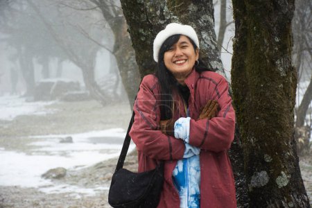 Foto de Las mujeres tailandesas viajeras visitan y posan retratos para tomar fotos y nieve cayendo en el bosque en el volcán Hanla Mountain o el Monte Halla en el Parque Nacional Hallasan en Jeju en Jeju-do, Corea del Sur - Imagen libre de derechos