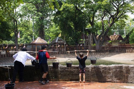 Téléchargez les photos : Les Thaïlandais portent de l'eau pour faire une offrande votive racheter un vœu à bouddha divinité ange souhait saint mystère culte mythe dans Bang Rachan village à Wat Pho Kao Ton à Singburi ville à Sing Buri, Thaïlande - en image libre de droit