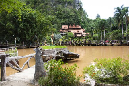 Téléchargez les photos : Ancien bâtiment en bois style thaï et jardin jardin parc avec lac montagne pour les voyageurs Voyage respat visite priant dans le temple Wat Tham Khao Wong à Ban Rai ville à Uthai Thani, Thaïlande - en image libre de droit