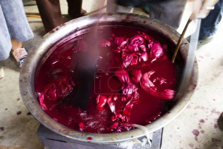Artiste thaïlandais travaillant batik ikat et teinture cravate couleur rose naturelle de la gomme laque bouillante en atelier artisanal et atelier artisanal à Baan Phu Chuang à Ban Rai à Uthai Thani, Thaïlande