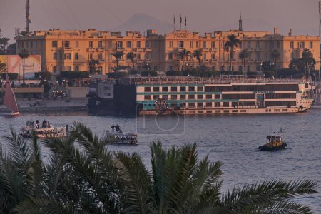 Photo for Luxor ,Egypt sunset shot from west bank showing Nile river with cruise ships , Feluccas and Winter palace hotel  in east bank - Royalty Free Image