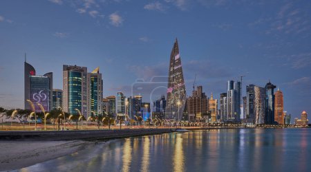 Foto de Doha Catar skyline desde el paseo corniche al atardecer mostrando las luces de los rascacielos de West Bay reflejadas en el golfo árabe - Imagen libre de derechos