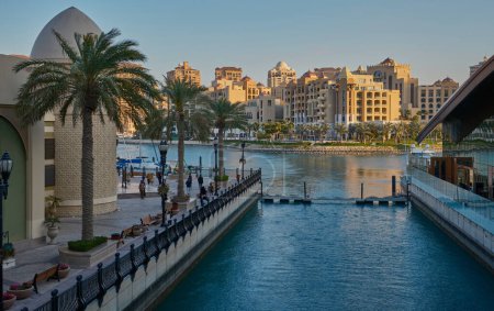 Téléchargez les photos : Doha, Qatar- Mars 1 2024 : Porto Arabia Marina dans La photo de l'après-midi perle montrant l'architecture unique des bâtiments avec des canaux d'eau, Yachts et les gens qui marchent - en image libre de droit