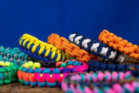 Photo for Lots of braided paracord bracelets on a blue background. Handmade, creative design. - Royalty Free Image