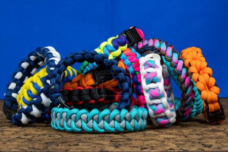Photo for Lots of braided paracord bracelets on a blue background. Handmade, creative design. - Royalty Free Image