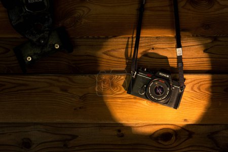 Téléchargez les photos : Vieille caméra sur une surface en bois. Fond en bois. Lumière et ombre. - en image libre de droit
