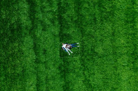 Téléchargez les photos : Un couple amoureux sur une grande prairie verte dans le parc. Vue de drone du bonheur et de la sérénité. - en image libre de droit